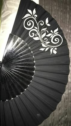 a black fan sitting on top of a bed next to a wooden wall with white designs