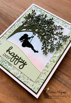 a card with a silhouette of a girl swinging on a tree and the words happy