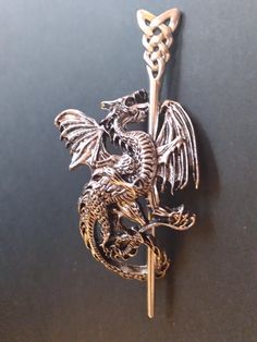 a silver dragon brooch with a gold chain