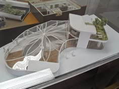 an architectural model of a building on display in a glass case with other buildings behind it