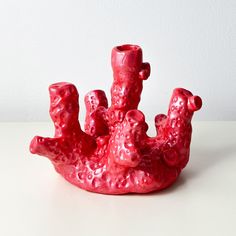 a red vase sitting on top of a white table