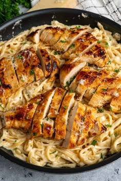 chicken and pasta in a skillet with parsley on the side, ready to be eaten