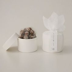 a white container filled with chocolates next to a box of wrapped cookies on top of a table