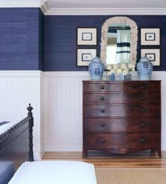 a bedroom with blue and white walls, a wooden dresser, and pictures on the wall