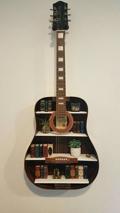 a guitar shaped book shelf with books on it's sides and a plant in the middle