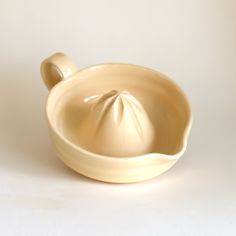 a cream colored ceramic bowl with two spoons in the bottom and one on the side