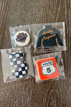 four decorated cookies in plastic bags on a wooden table with the name harley davidson written on them