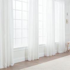 a living room with white walls and curtains