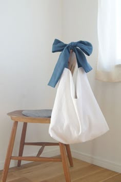 a wooden chair with a white bag hanging from it's back and a blue bow on top