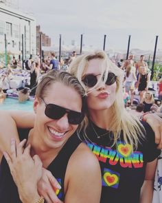 a man and woman posing for a photo in front of a pool at an outdoor event