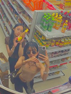 two women taking a selfie in a grocery store with their cell phone and camera