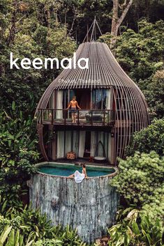 a man standing on the balcony of a house in the jungle with trees surrounding it