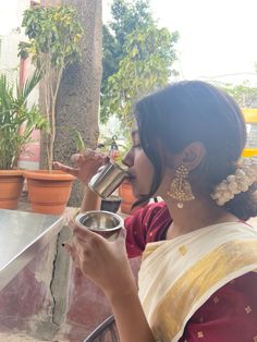 a woman drinking from a cup while sitting at a table