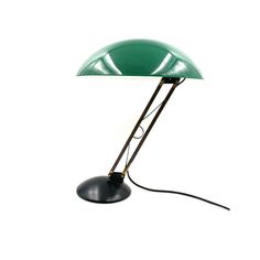 a green table lamp sitting on top of a white floor next to a black light