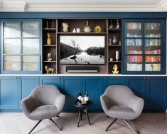 two chairs and a table in front of a large entertainment center with blue painted walls