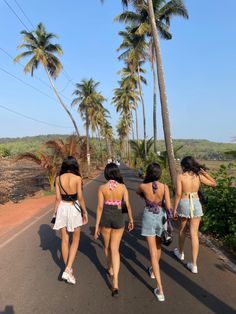 three girls walking down the road with palm trees in the background