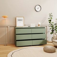 a living room with a green dresser next to a white chair and clock on the wall