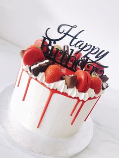 a birthday cake with strawberries and chocolate drips