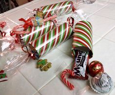 candy wrapped in plastic and tied up with christmas decorations on the table next to them