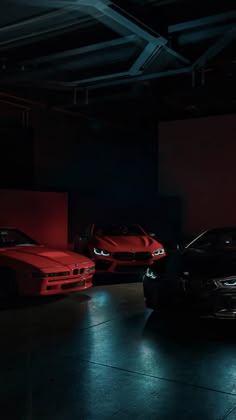 three cars parked in a dark garage with red lights on the floor and one black car