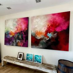 two paintings are hanging on the wall next to a wooden bench in a living room