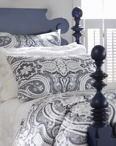 a bed with blue headboard and white comforter on it's side in a bedroom