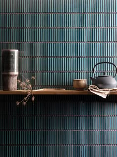 a shelf with pots and cups on it in front of a blue wallpapered background