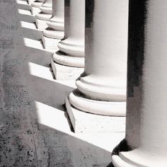 the columns are lined up against the wall and casting shadows on the concrete flooring