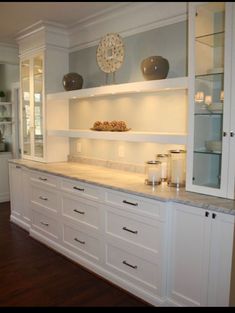 a kitchen with white cabinets and marble counter tops