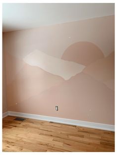 an empty room with wood flooring and painted mountains on the wall in pink tones