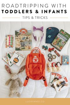 an orange backpack sitting on top of a bed next to books and other items in front of it