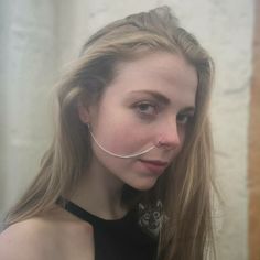 a woman with long blonde hair wearing a nose chain