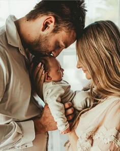 a man and woman holding a baby in their arms