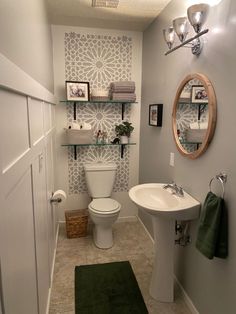 a white toilet sitting in a bathroom next to a sink under a mirror on a wall