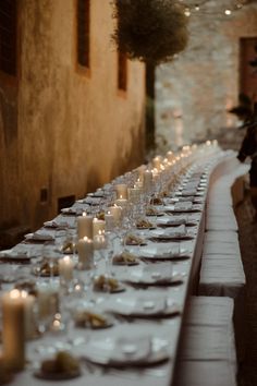 the long table is set with many plates and glasses on it, along with candles