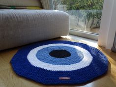 a crocheted blue rug on the floor in front of a couch and window