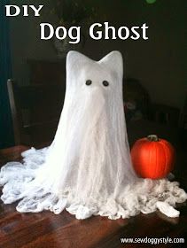 a white ghost sitting on top of a wooden table next to a pumpkin