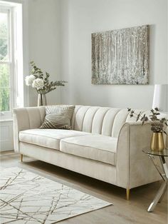 a living room with a white couch, rug and large painting on the wall above it