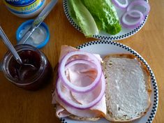 a sandwich with onions, meat and lettuce is on a plate next to a jar of mayonnaise