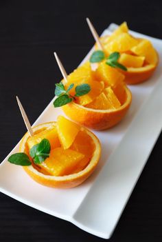 small oranges with toothpicks in them on a white plate