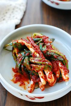 a white plate topped with green beans covered in marinara sauce on top of a wooden table