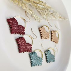 four pairs of leaf earrings on a white plate