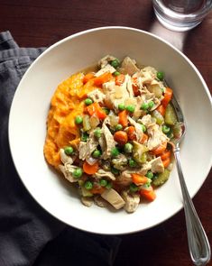 a white bowl filled with chicken, peas and mashed potatoes