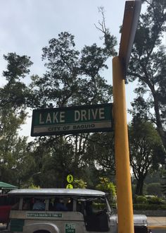 a street sign that says lake drive on the side of a road with trees in the background