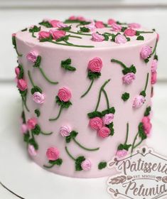 a pink cake with green leaves and flowers on it