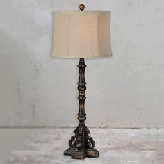 a lamp that is on top of a white surface with a beige shade over it