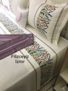 the bed is made with white sheets and purple trimmings, along with decorative pillows