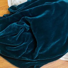 a pile of clothes sitting on top of a wooden floor next to a white pillow