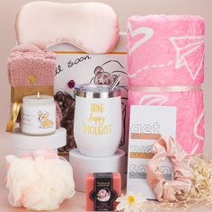 a pink gift basket with personal care items on it, including towels, soaps and candles