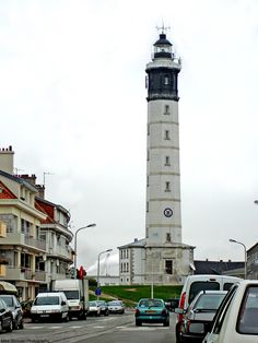 cars are parked in front of a light house